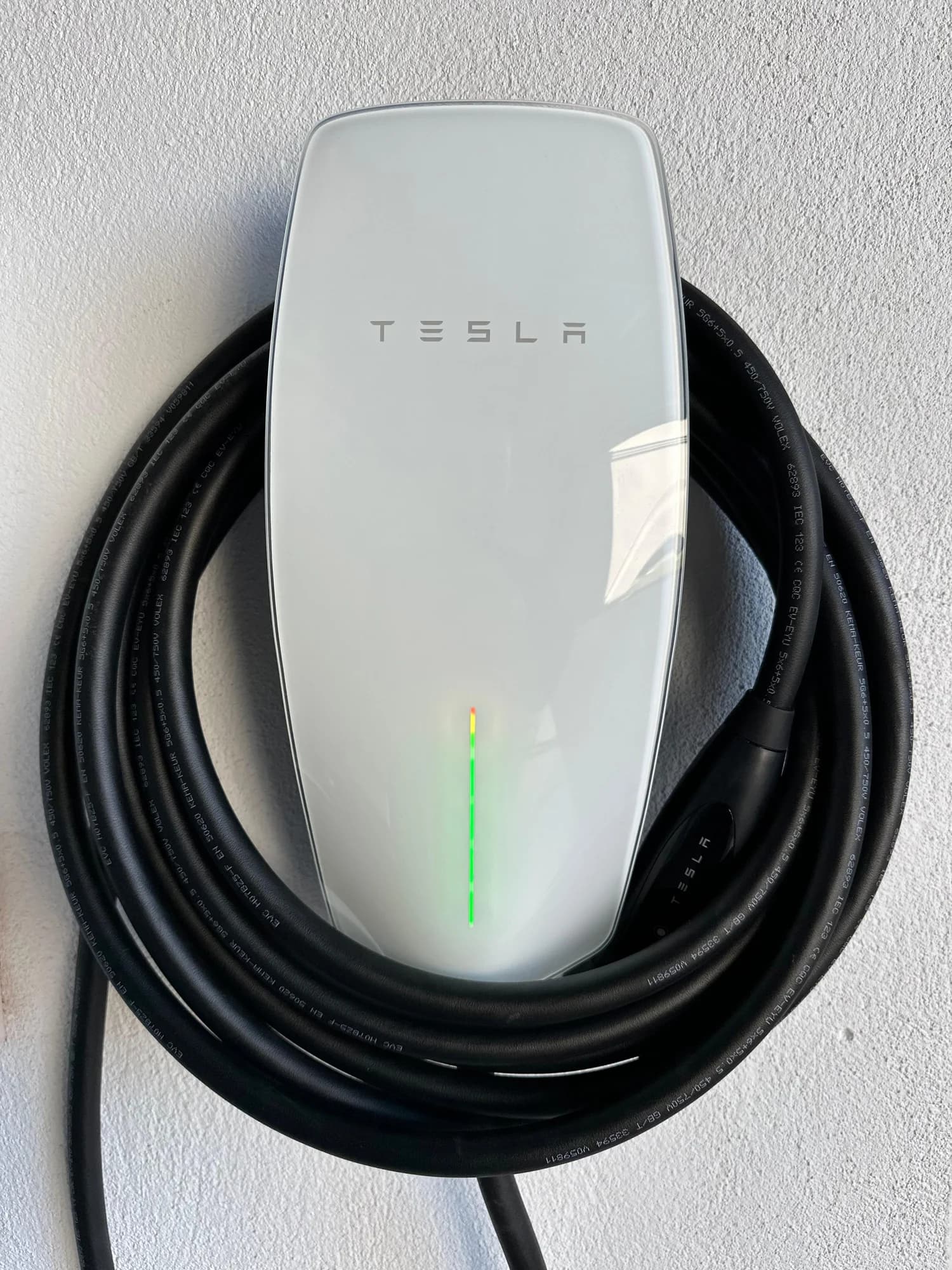 Tesla Wall Connector with its charging cable coiled, installed on a rendered wall by Melbourne Power Group